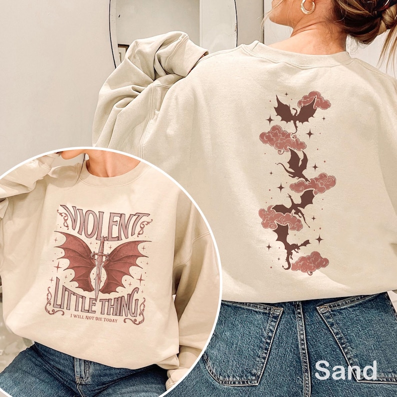 May include: Sand-colored sweatshirt with a graphic on the front that says "Violent Little Thing" with a sword and bat wings. The back features a design of dragons and clouds. The sweatshirt is made of a soft material.
