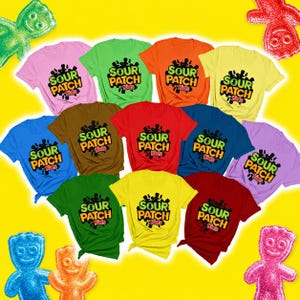 May include: A collection of eleven short-sleeved t-shirts in various solid colors, each featuring the Sour Patch Kids logo printed in black, green, and orange on the chest, arranged against a bright yellow background with candy figures.