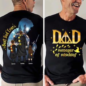 May include: Black t-shirt with a gold design that says "DAD manager of mischief" with a wizard theme. The back of the shirt has a silhouette of a wizard family with the text "Best Dad Ever" and the names James, Daddy, and Emma.