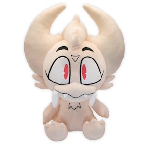 Puede incluir: Un peluche que representa una criatura de dibujos animados con ojos grandes y abiertos, pupilas rojas y colmillos blancos prominentes. El juguete tiene cuernos grandes y curvados y brazos y pies pequeños. El peluche es de color beige claro con contornos negros.