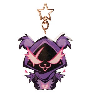 May include: A purple and black glittery keychain featuring a cartoon character with pink accents and a star-shaped clasp. The character has a hooded design with stylized eyes and a small heart detail.
