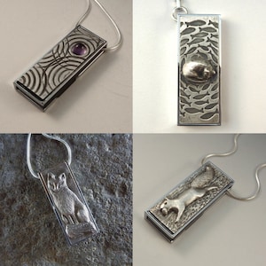 May include: Four silver necklaces with different pendants. The pendants are rectangular and feature various designs, including a swirling pattern with a purple gemstone, a school of fish, a fox, and a squirrel.