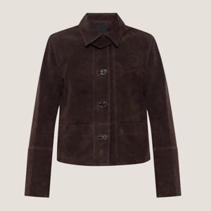 May include: A dark brown suede jacket with a classic collar and button-down closure. The jacket features long sleeves with buttoned cuffs and a tailored fit. The garment has a minimalist design, suitable for various occasions.