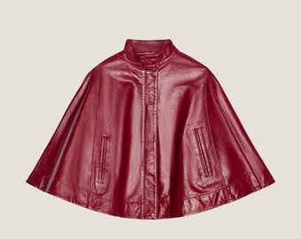 May include: A burgundy leather cape with a zipper closure and two pockets. The cape has a rounded hemline.