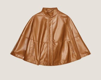 May include: A brown leather cape with a high collar and a zipper closure. The cape has a short, fitted silhouette and a flared hem.