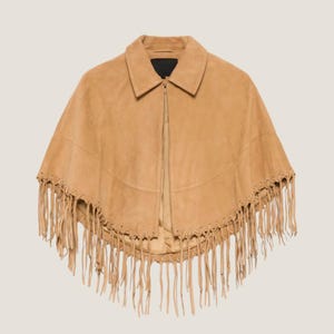 May include: A tan suede cape with a collar and a zipper closure. The cape features long fringe along the bottom edge. The garment is a neutral color and is suitable for various outfits.