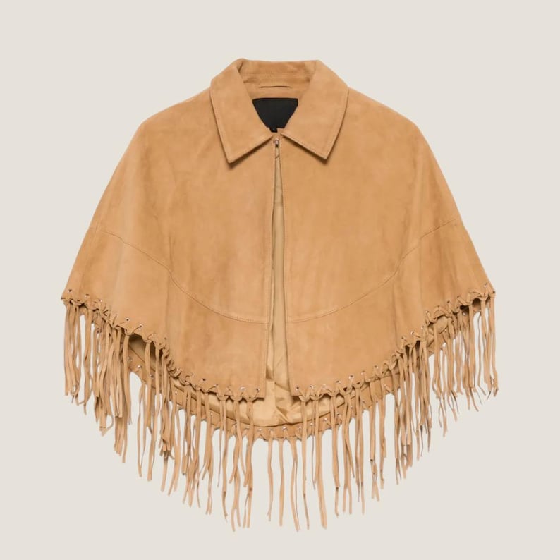 May include: A tan suede cape with a collar and a zipper closure. The cape features long fringe along the bottom edge. The garment is a neutral color and is suitable for various outfits.