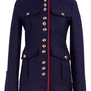 Puede incluir: Una chaqueta de estilo militar azul marino con ribete rojo y botones dorados.