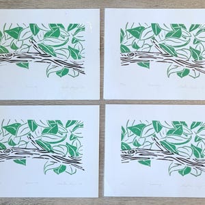 May include: Four identical prints of a linocut artwork. Each print features a stylized depiction of green leaves and a brown branch against a white background. The artist's signature and title are visible.