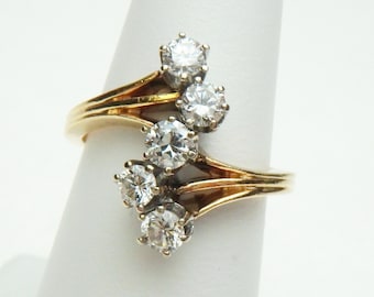 May include: A gold ring with five clear round stones set in a curved design.