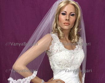May include: A white bridal veil with a lace trim. The veil is worn by a mannequin with blonde hair and a white wedding dress.