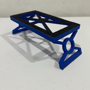 May include: A small, blue, 3D printed table with a black top. The table has a geometric design and is made of plastic.