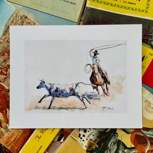 May include: A watercolor painting of a cowboy on horseback roping a calf. The cowboy is wearing a blue shirt and jeans, and the calf is white with brown spots. The painting is set against a light brown background.