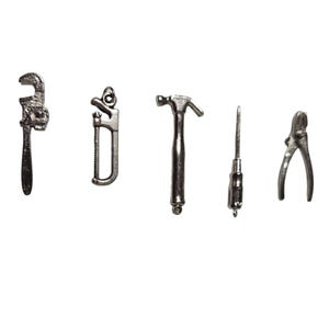 Könnte beinhalten: Eine Sammlung von silberfarbenen Miniaturwerkzeugen, darunter ein Schraubenschlüssel, eine Säge, ein Hammer, ein Schraubendreher und eine Zange, vor weißem Hintergrund. Diese kleinen Werkzeuge sind wahrscheinlich Charms oder Dekorationsartikel.