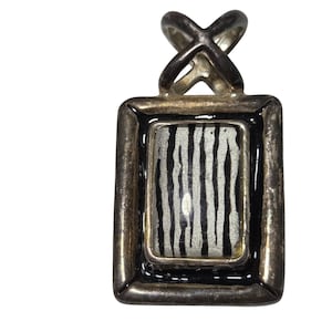 May include: Silver-toned pendant with a rectangular frame and a black border. The center features a zebra stripe pattern in black and white. The pendant has a decorative bail.