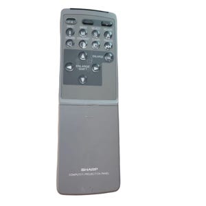 May include: A gray Sharp computer projection panel remote control. The remote has several buttons labeled "Input", "Menu", "Select", "Adjust", "Volume", "Contrast", "Clear", and "Freeze". It also has buttons for "Enlarge" and "Shift".