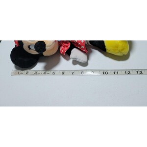 May include: A plush toy of Mickey Mouse's girlfriend Minnie Mouse. She is wearing a red dress with white polka dots and a white bow. She is lying on her side with her head resting on her arm. The toy is about 12 inches long.