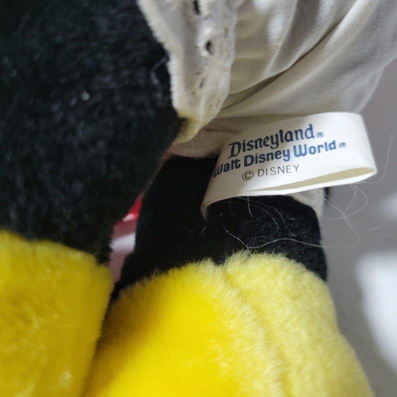 May include: Black and yellow plush toy with a white tag that reads "Disneyland Walt Disney World Disney".