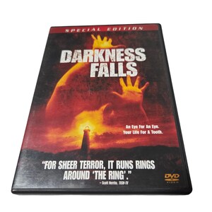 Könnte beinhalten: DVD-Hülle für den Film "Darkness Falls". Das Cover zeigt einen rot-orangen Hintergrund mit einer Silhouette und dem Titel in großen weißen Buchstaben. Der Slogan lautet: "An Eye For An Eye. Your Life For A Tooth."