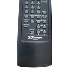 May include: A black Emerson remote control with numerous buttons, including channel, volume, and mute controls. The remote has a curved design and features the Emerson logo and model number 6142-07601.