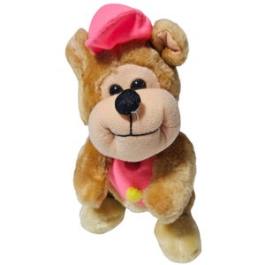 Oso de peluche vintage de 23 cm con gorro rosa, camisa y pompón amarillo.