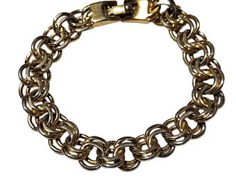 May include: A gold-toned metal chain bracelet featuring a double-link design with a polished finish. The bracelet is constructed from repeating circular links that create a textured, woven appearance and includes a secure, integrated box clasp closure.