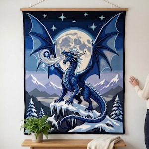 Può includere: Un arazzo da parete rettangolare raffigurante un grande drago blu appollaiato su una vetta innevata. Il drago espira un soffio gelido su uno sfondo con luna piena, cielo stellato e montagne innevate con alberi di pino.