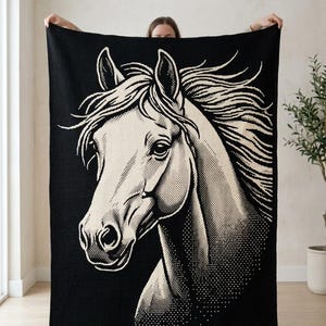 May include: A rectangular woven blanket featuring a large, high-contrast graphic of a horse head in cream against a solid black background. The design utilizes a dot-matrix style pattern to create shading and texture across the horse's mane and face.