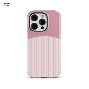 Puede incluir: Una funda para teléfono con un diseño de dos tonos, con una sección superior de color rosa polvoriento sólido y una sección inferior de color rosa claro decorada con rayas verticales. El área de la cámara es negra y el texto THE ONE CASE es visible.
