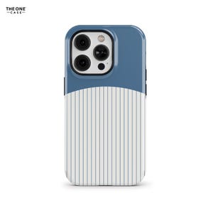 Puede incluir: Una funda para smartphone con una sección superior azul sólido y una sección inferior blanca con finas rayas verticales azules. El área del módulo de la cámara está recortada, revelando tres lentes circulares y un flash. El texto THE ONE CASE es visible.
