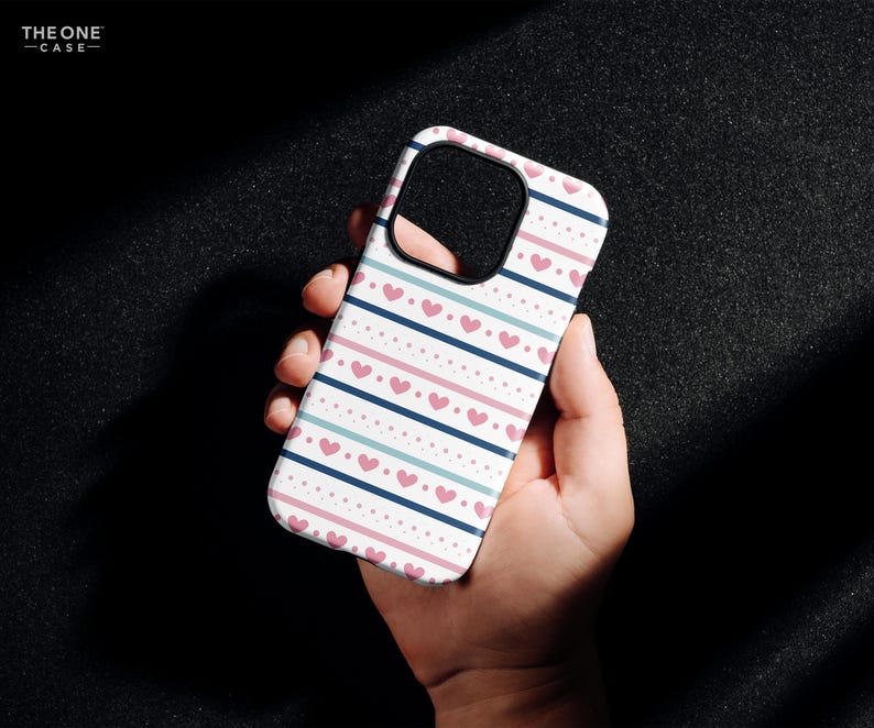 May include: A white phone case with a pink and blue striped pattern and pink hearts. The case is designed for an iPhone.