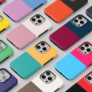 May include: A selection of two-tone phone cases in various colours, including yellow, pink, green, and blue. The cases have a glossy finish and are arranged in a grid pattern. The cases are designed for a smartphone.