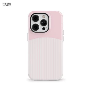 Puede incluir: Una funda para teléfono con diseño bicolor que presenta una sección superior en rosa claro sólido y una sección inferior blanca con finas rayas verticales rosas. La funda incluye un recorte negro para la cámara con tres lentes.