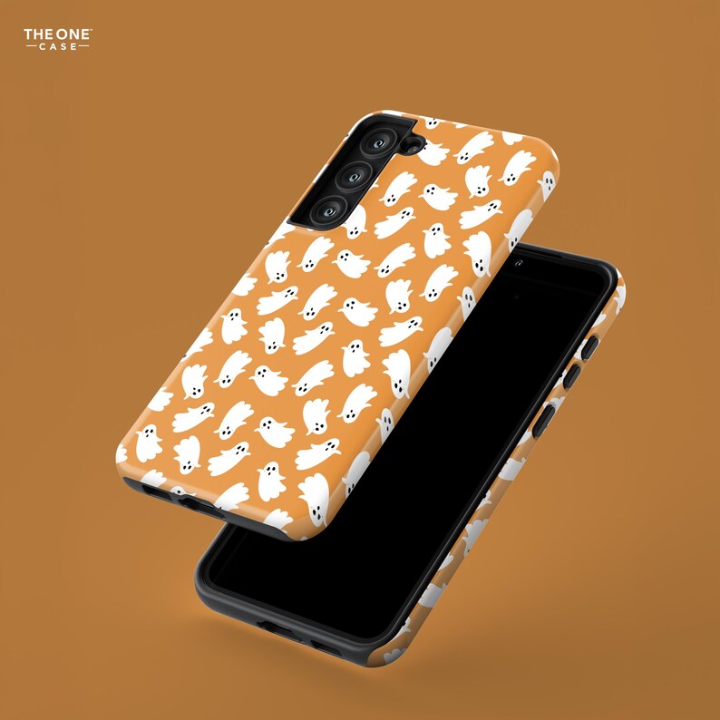 May include: Two orange phone cases with a white ghost pattern. The phone cases are black and have a glossy finish. The cases are designed to fit a smartphone and are shown against an orange background.