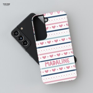 May include: A white phone case with a pink and blue striped pattern and pink hearts. The name "MADALINE" is written in pink letters on the case.