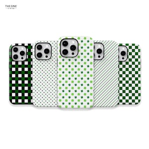 May include: A collection of phone cases with various patterns. Designs include green and white polka dots, shamrocks, diagonal stripes, and a checkered pattern. The cases are white with black camera cutouts and a black border.
