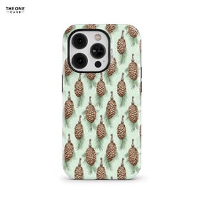 May include: A green phone case with a pattern of brown pine cones on a white background. The case has a cutout for the camera lens.