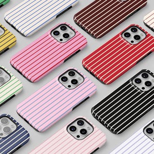 Op de afbeelding: Een verzameling gestreepte telefoonhoesjes in diverse kleuren, waaronder geel, roze, rood, zwart en blauw. De hoesjes hebben een strak ontwerp en zijn in een rasterpatroon gerangschikt, wat de verscheidenheid aan opties laat zien.