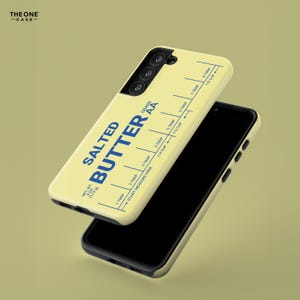 Pu&ograve; includere: Una custodia per telefono giallo chiaro con un design a tema burro. La custodia presenta le parole "SALTED BUTTER" in blu, insieme a una guida di misurazione in cucchiai e tazze. La custodia ha anche il testo "NET WT. 4 OZ (113g)".