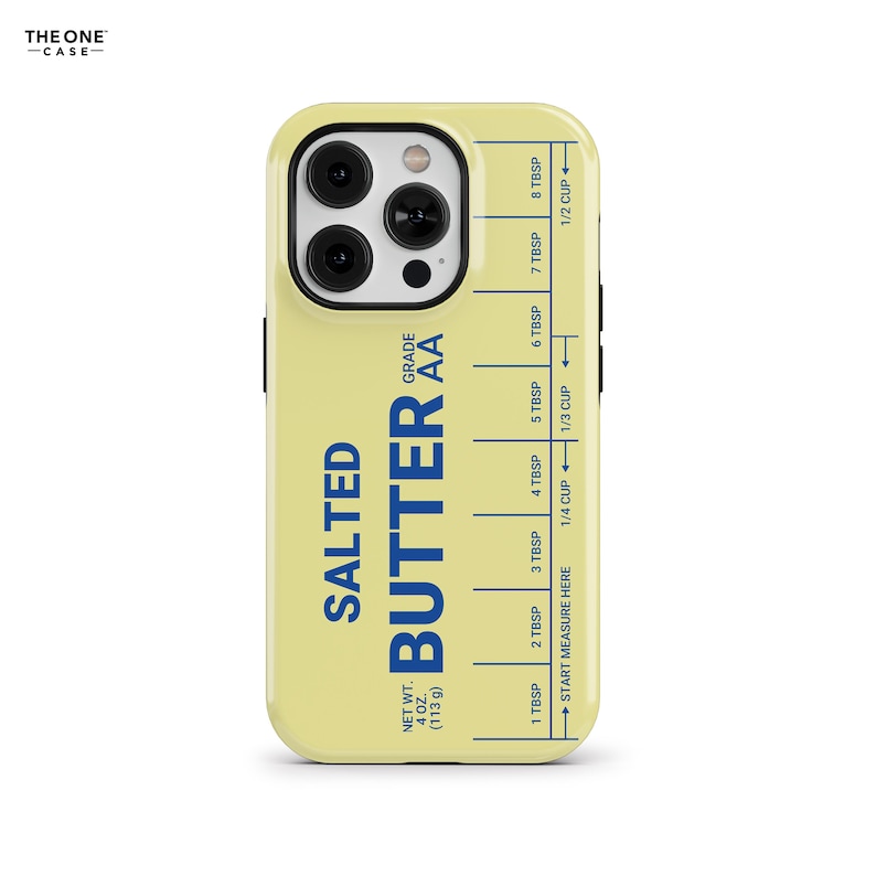 Pu&ograve; includere: Custodia per telefono gialla con un design a forma di panetto di burro. La custodia presenta le parole "SALTED BUTTER" in blu, insieme a segni di misurazione in cucchiai e tazze. La custodia ha anche il testo "NET WT. 4 OZ. (113 g)".