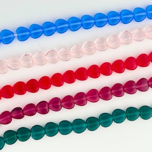 May include: Five strands of heart-shaped beads in different colors: blue, pink, red, burgundy, and green. The beads are made of glass and have a glossy finish.