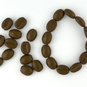 May include: A brown coffee bean bracelet with a circle of coffee beans and a scattering of coffee beans on a white background.