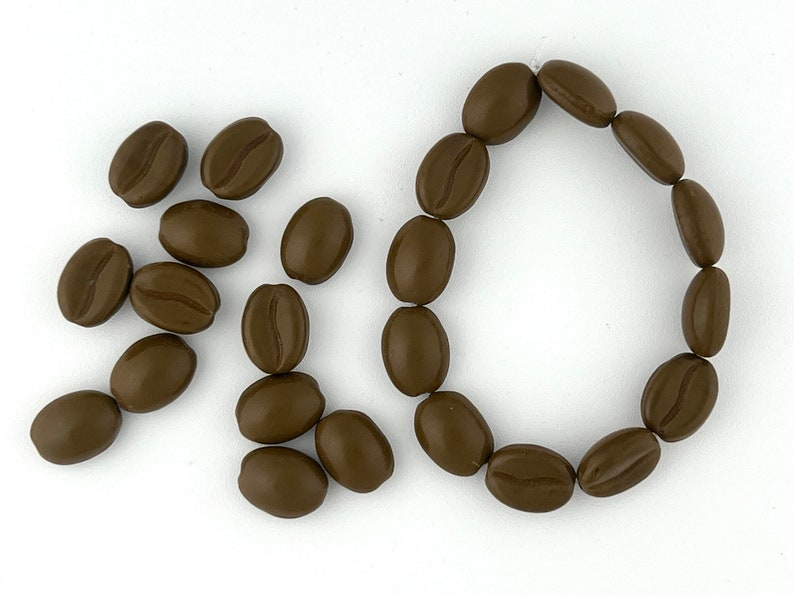 May include: A brown coffee bean bracelet with a circle of coffee beans and a scattering of coffee beans on a white background.
