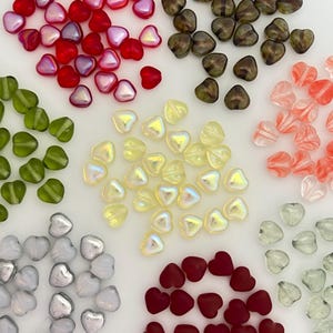 May include: A collection of heart-shaped beads in various colors, including red, green, yellow, silver, and brown. The beads are translucent and have a glossy finish. Ideal for jewelry making or craft projects.