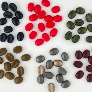 May include: Assortment of coffee bean shaped beads in various colors, including red, brown, green, burgundy, and silver.