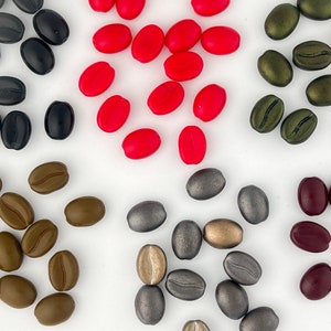 May include: Assortment of colorful coffee bean shaped beads in red, brown, green, black, and silver.