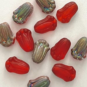 May include: Assortment of glass beads in red and iridescent colors. The beads are shaped like a flower bud and have a textured surface.