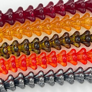 May include: Five strands of glass beads in various colors, including red, orange, yellow, green, and gray. The beads are shaped like small, pointed flowers.