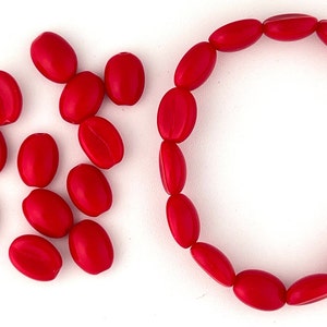 May include: A red oval-shaped bead bracelet with a circle of beads and a pile of loose beads.