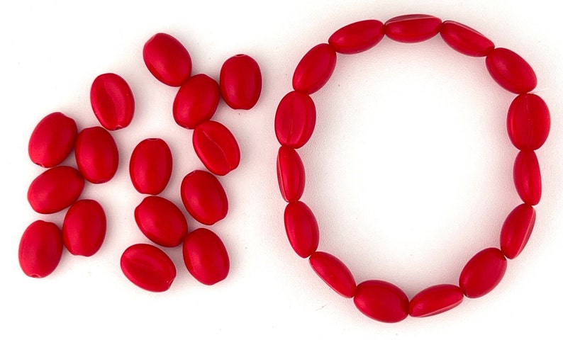 May include: A red oval-shaped bead bracelet with a circle of beads and a pile of loose beads.